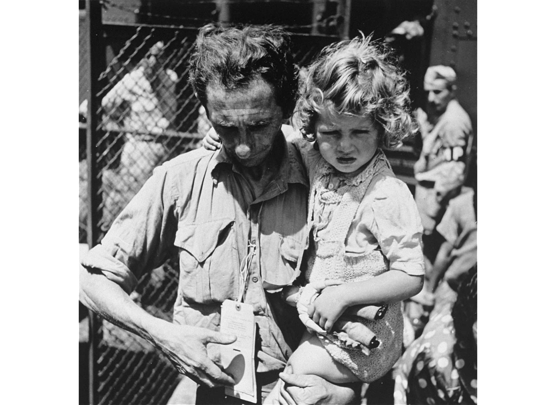 A father carries his daughter on arrival at the Fort Ontario Emergency Refugee Shelter, August 1944. National Archives and Records Administration, College Park