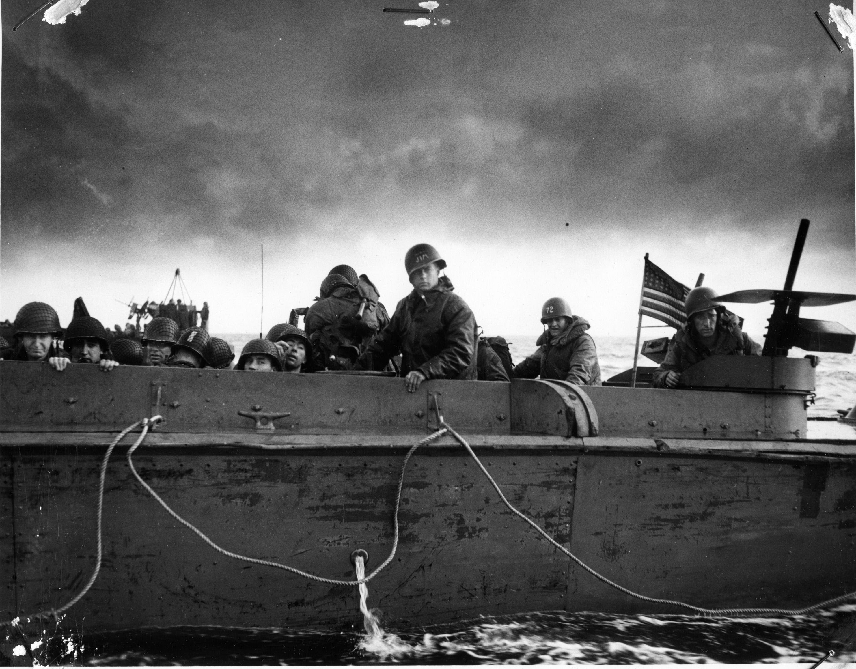 Soldiers looking over the top of a boat during D-Day