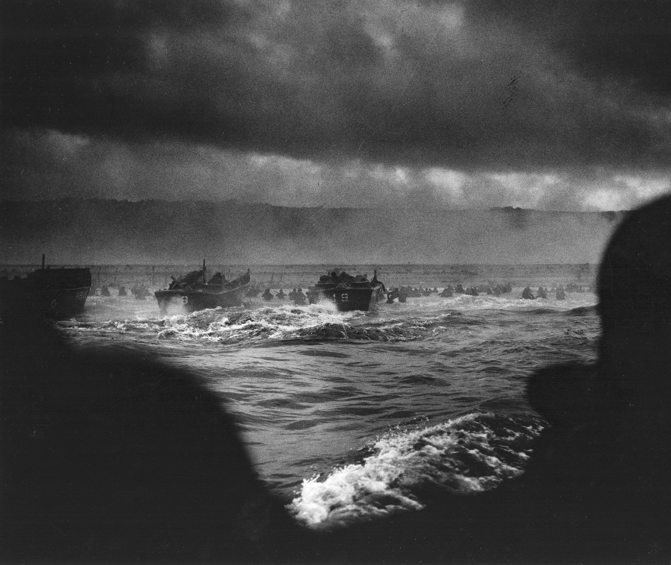 View from a boat as American boats and soldiers storm the shores on D-Day.