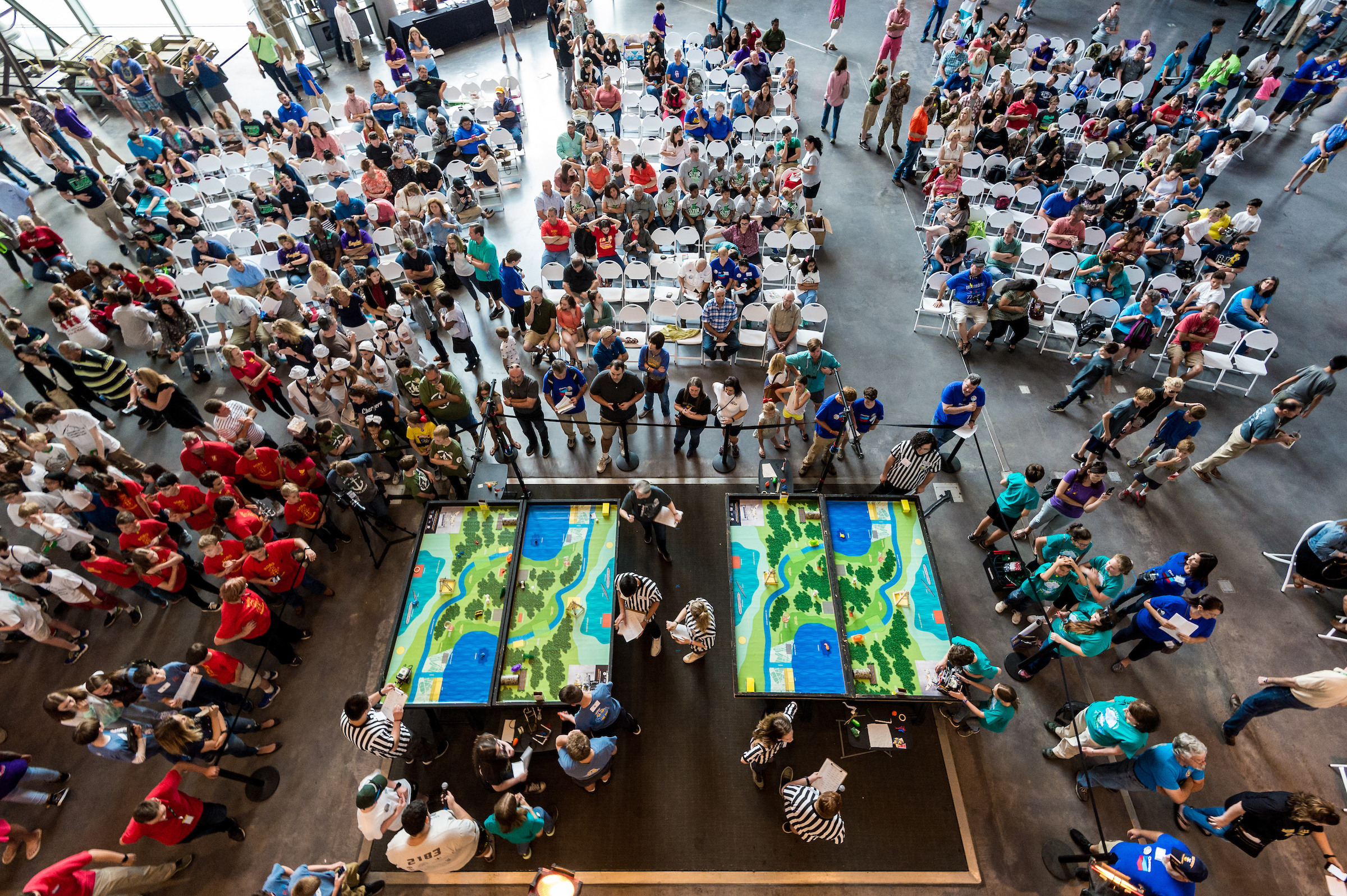 A large crowd of students and spectators watch as robotics teams compete at the National WWII Museum Robotics Challenge