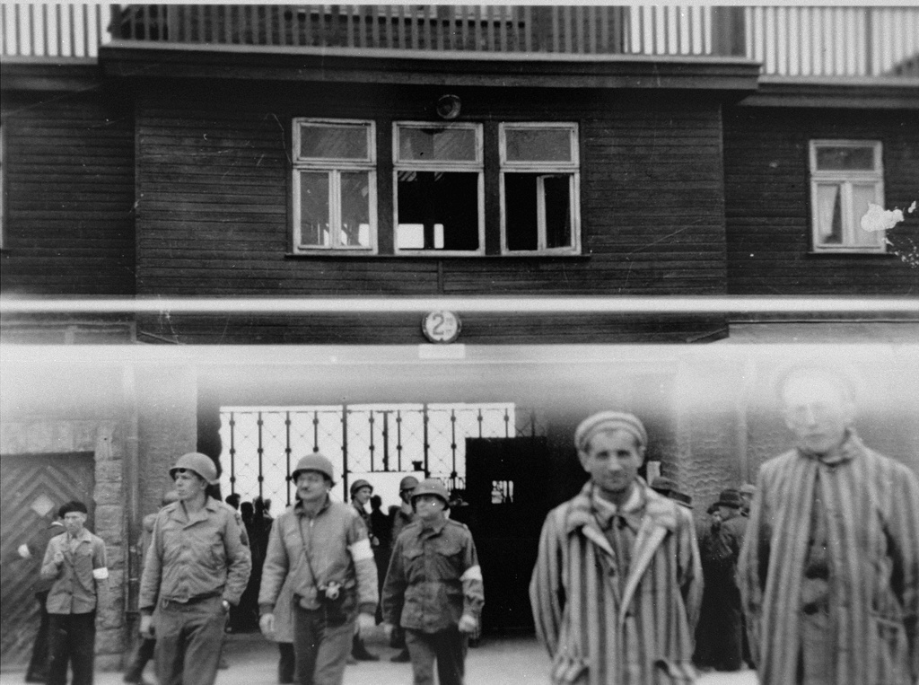 American soldiers and survivors stand by the entrance of Buchenwald