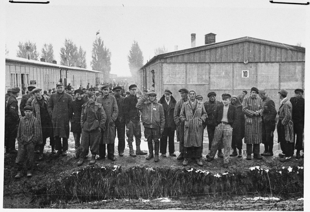 Group portrait of survivors standing next to the moat in the Dachau concentration camp