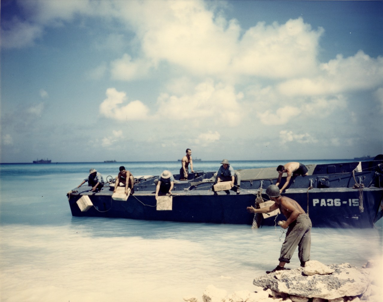 Seabees lower Hercules powder explosives over the side of an LCVP during construction of the Eniwetok Atoll airfield