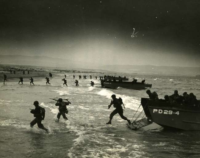 Soldiers run off landing boat onto beach