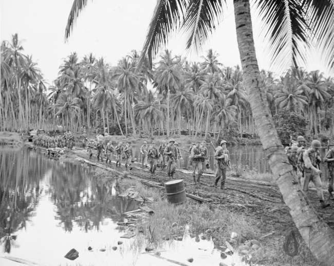 Soldiers walking by water at Guadalcanal during WWII