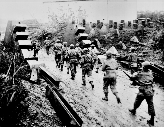 US troops marching through the remains of the Siegfried Line.