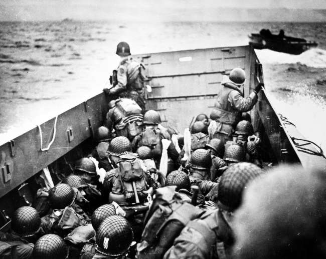 Troops crouch inside a LCVP landing craft