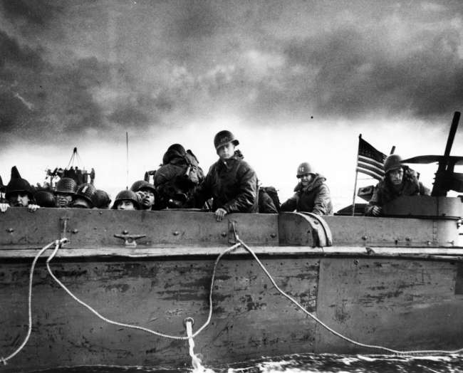 Troops and crewmen aboard a Coast Guard manned LCVP as it approaches a Normandy beach