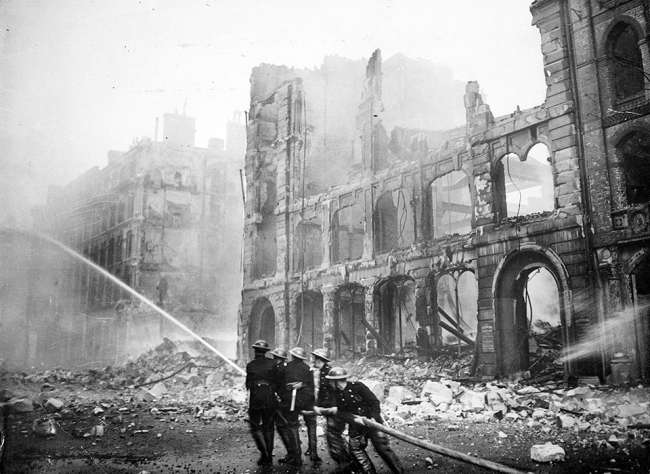 Firemen at work in bomb damaged street in London