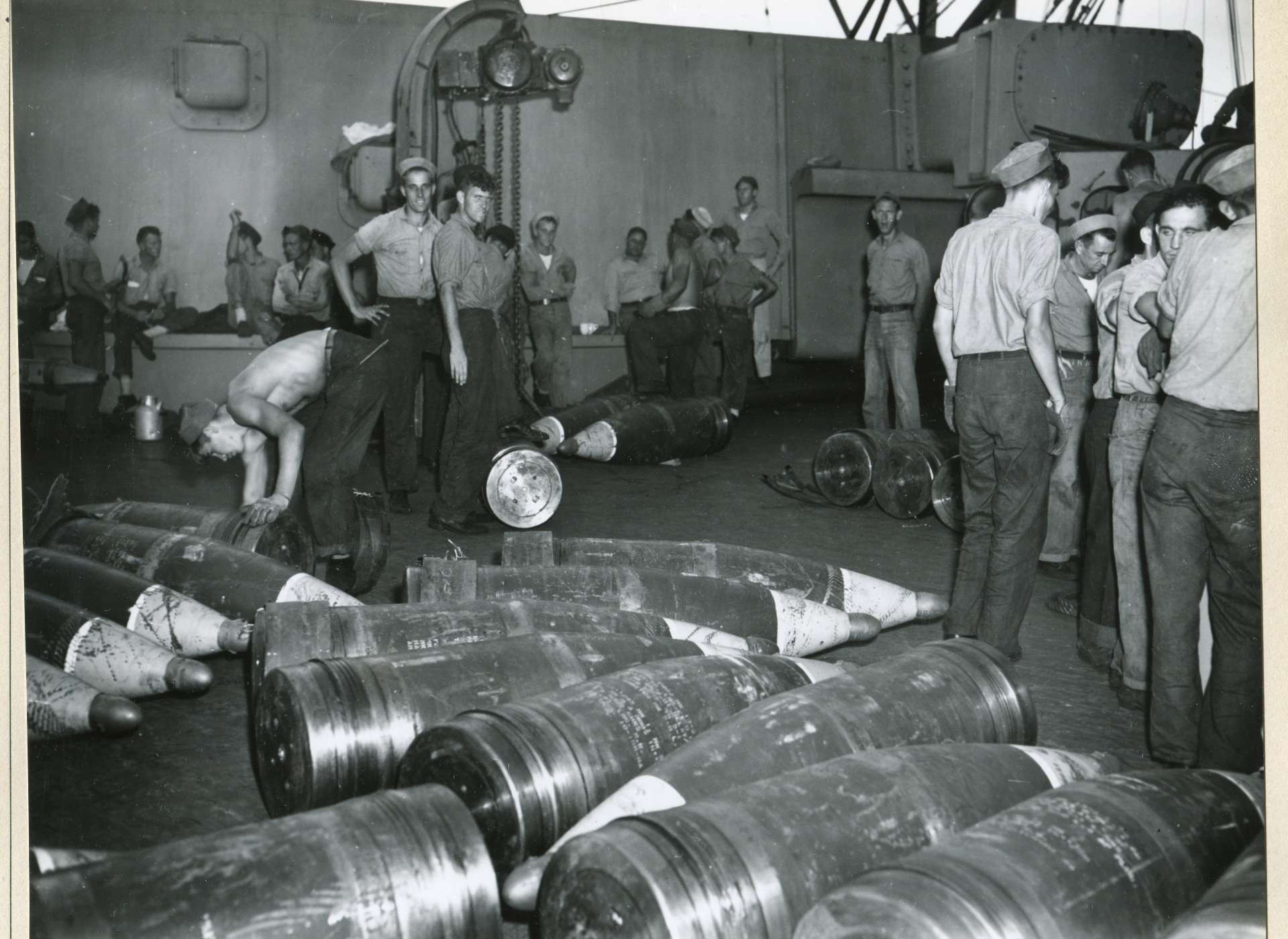 Sailors around 16-inch projectiles aboard an American battleship.