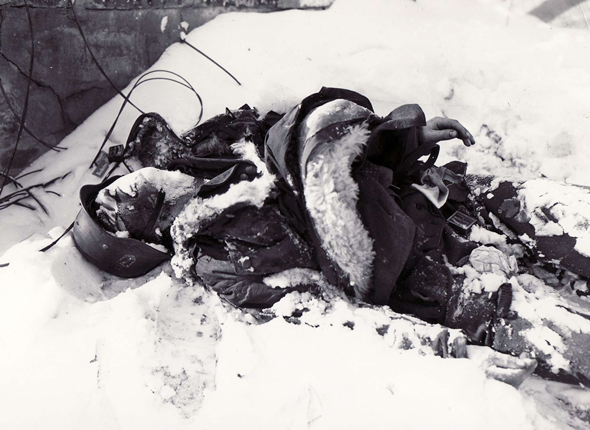 A Panzergrenadier of the Waffen SS lies buried in the snow following the fierce fighting near Elsenborn Ridge. The National WWII Museum Digital Collections.