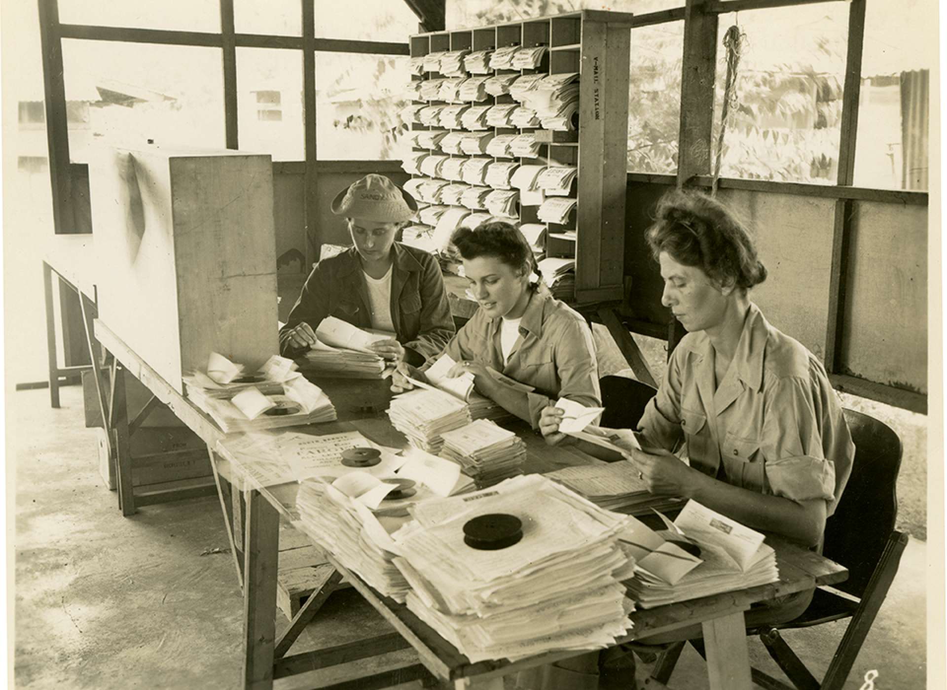 V-mail operation in the field at APO 929. “Here is a section of the opening and targeting operation. Targeting is simply preparing each group of letters with a State target so mail for each group of States can be sent to its proper finishing station in the States. Here also, are withdrawn all letters which will not photograph well. These, of necessity, must be sent by regular mail, which in this case means by air.” Port Moresby, Papua New Guinea. 1944