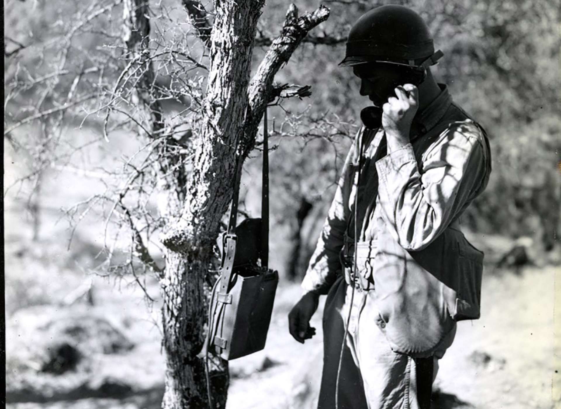 3-24-44. Ecklund. T/5 W. T. Gardner, 89 Sig Platoon, 89 Div, is testing a EE8A Field Telephone he has just installed at the new area of 89Div CP near Hill 2280 HLMR. HLMR MTN Man. R 168-9-44-659. Army Signal Corps photograph  Photographer: Ecklund. 24 March 1944. Gift in Memory of Maurice T. White, 2011.065.1909