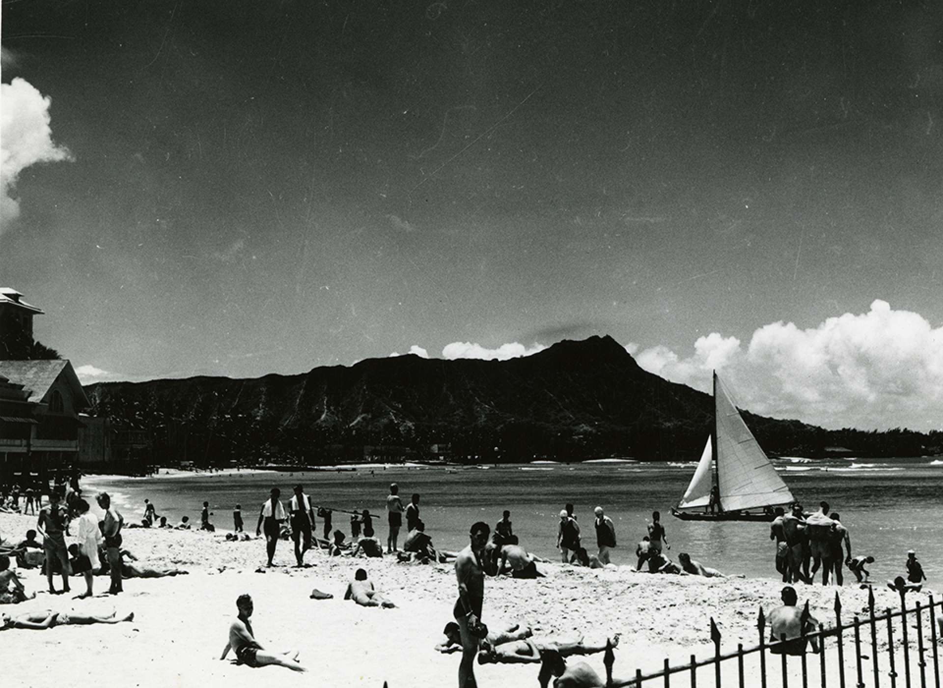 Sunbathers on Waikiki beach, Diamondhead in background. Honolulu, Hawaii