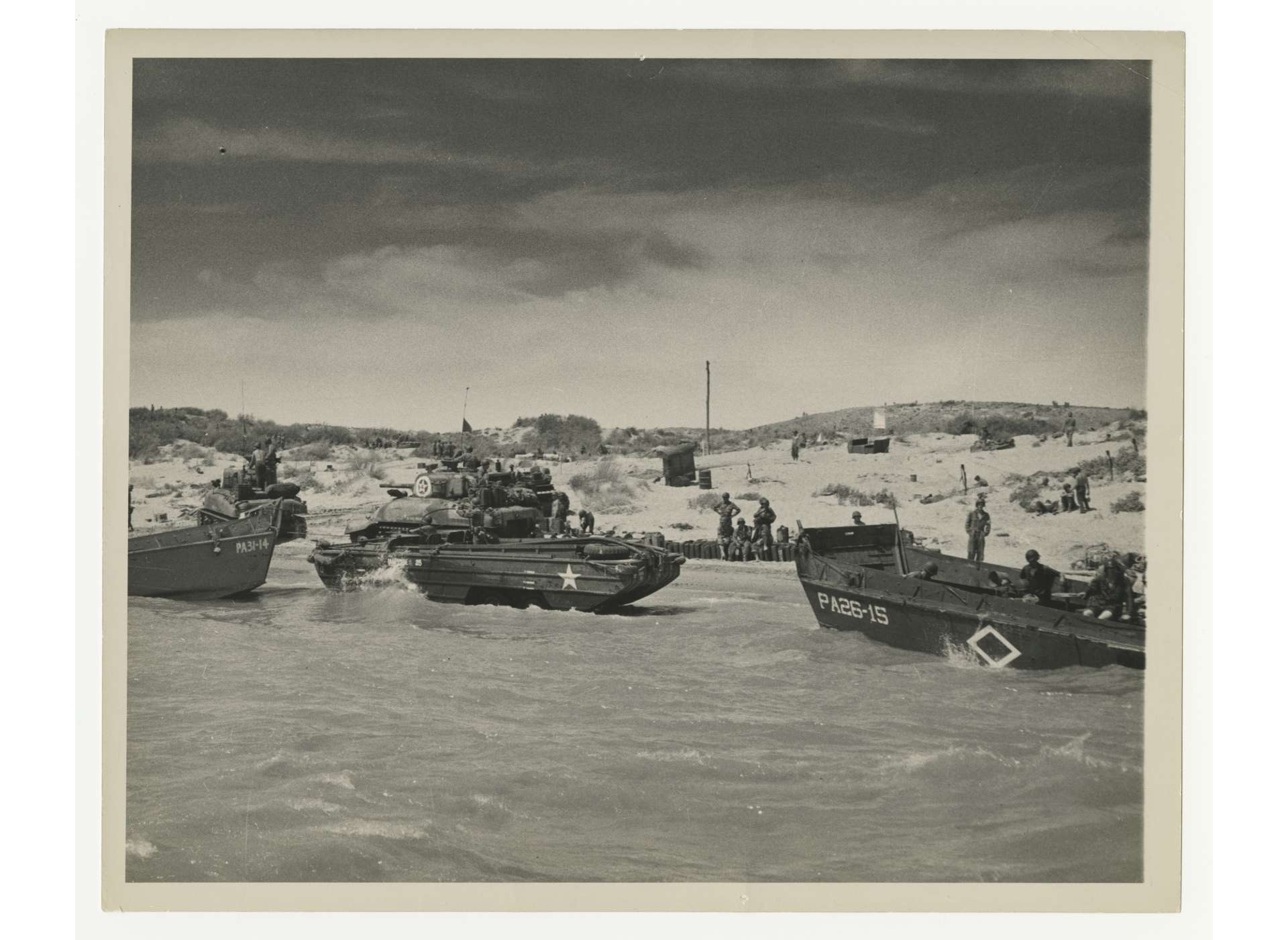 US LCVPs (Landing Craft Vehicle, Personnel), also known as “Higgins boats,” from USS Samuel Chase and USS Monrovia, an amphibious truck and a Sherman tank on Sicily, July 1943. Official US Coast Guard Photo, gift of Jeffrey and Mary Cole, from the Collection of The National WWII Museum, 2002.119.023.