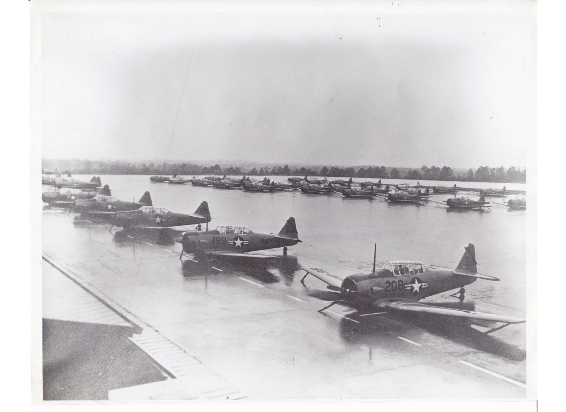 At a US Navy airfield in Florida, World War II vintage SNJ trainers are lashed to the tarmac on their bellies as a hurricane comes ashore in 1962. Courtesy National Naval Aviation Museum.