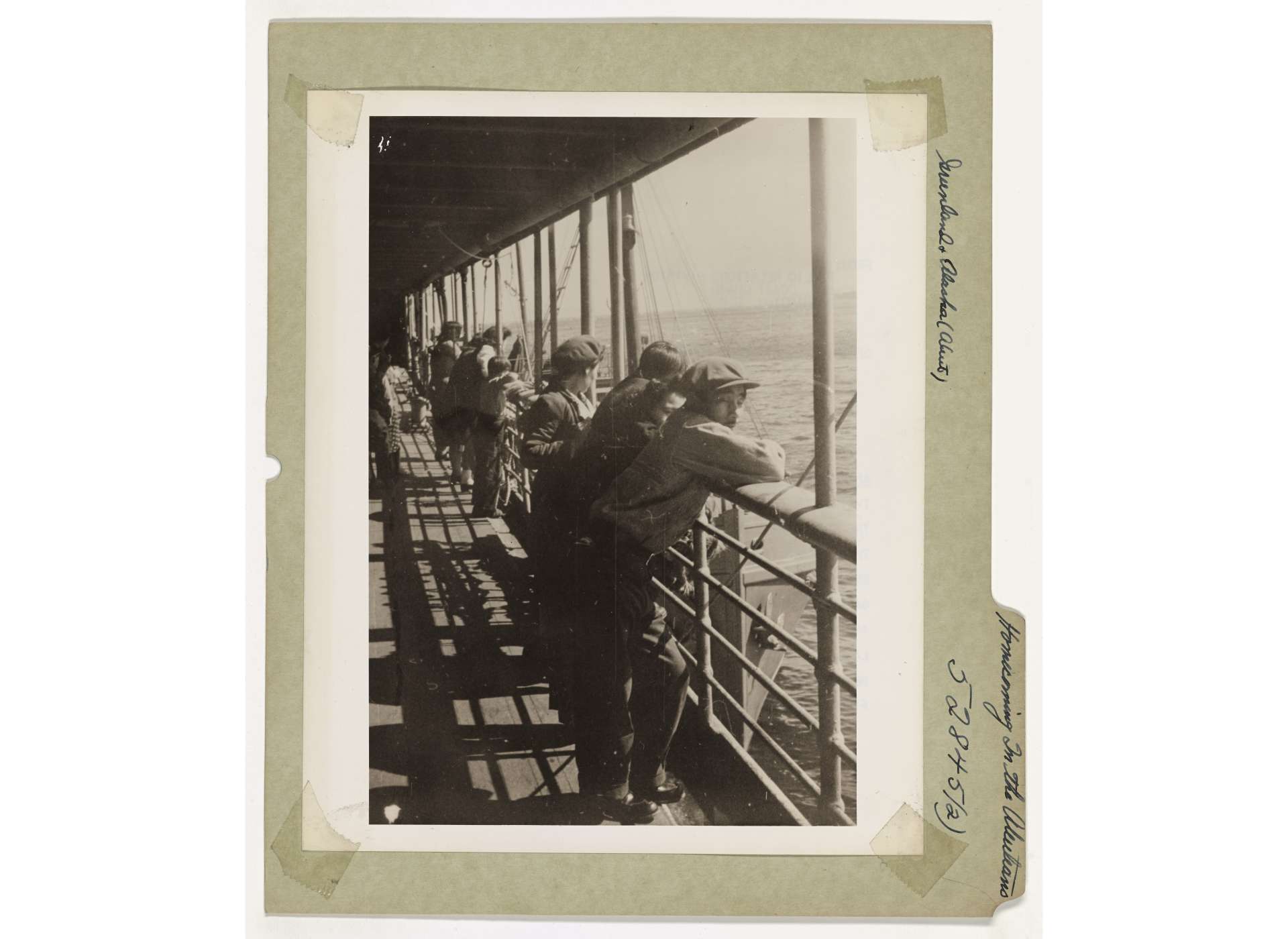 A group of Unangan men watch as they near St. Paul Island, their first glimpse of home after removal for nearly three years, May 28, 1945. Courtesy of the National Archives and Records Administration.