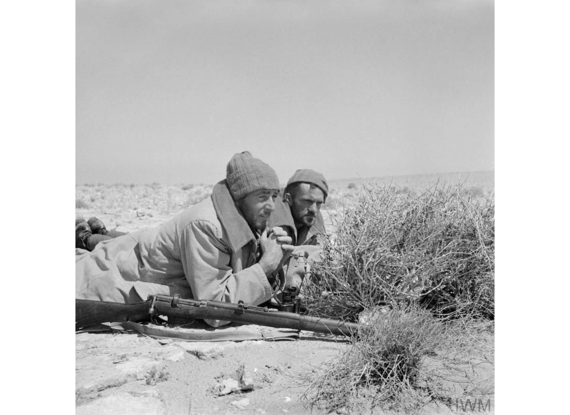 Two men of a LRDG patrol, dressed in greatcoats, on a road watch in North Africa, 25 May 1942.