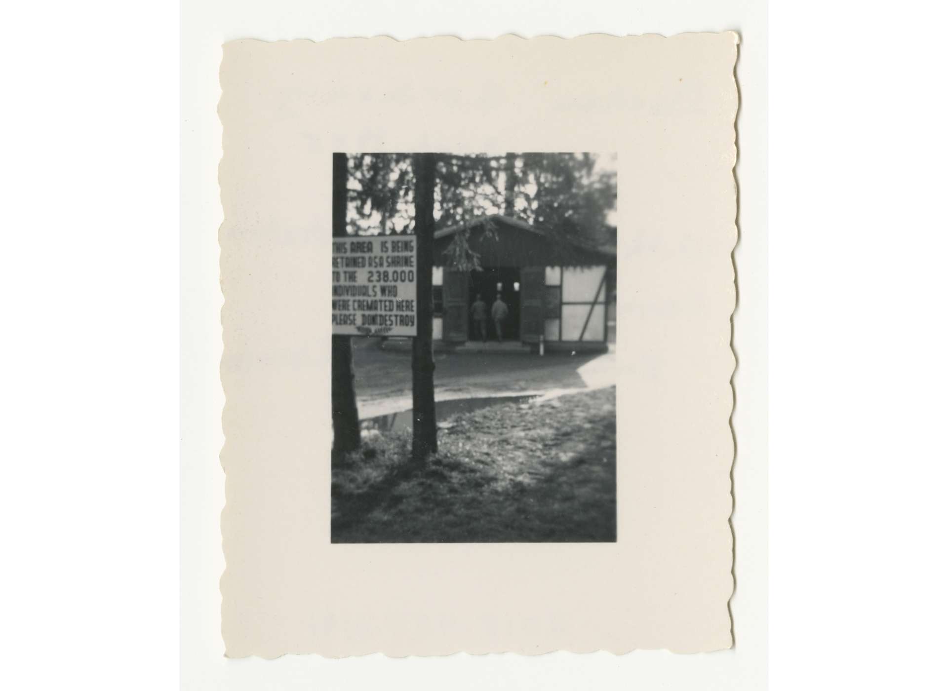 US personnel enter the gas chamber at Dachau. The sign with death statistics in the foreground is not correct. Over 41,000 people perished at Dachau. US Army Signal Corps Photo, Gift in Memory of Jack Hershkowitz, from the Collection of The National World War II Museum, 2015.457.114.