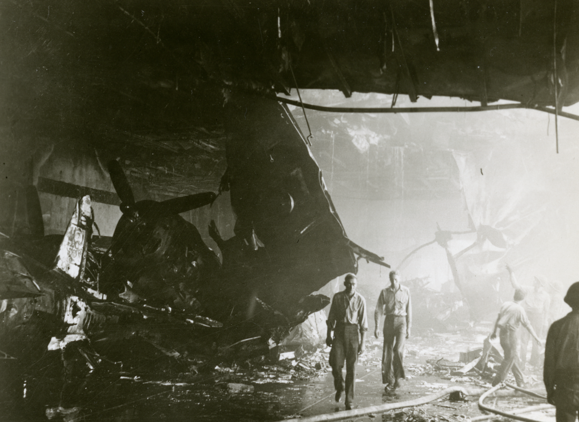 Sailors walk through the wrecked hangar deck of USS Bunker Hill (CV-17) following a kamikaze attack during the Battle of Okinawa. US Navy official photograph. The National WWII Museum, Gift of Thomas J. Hanlon, Accession #2013.495.412