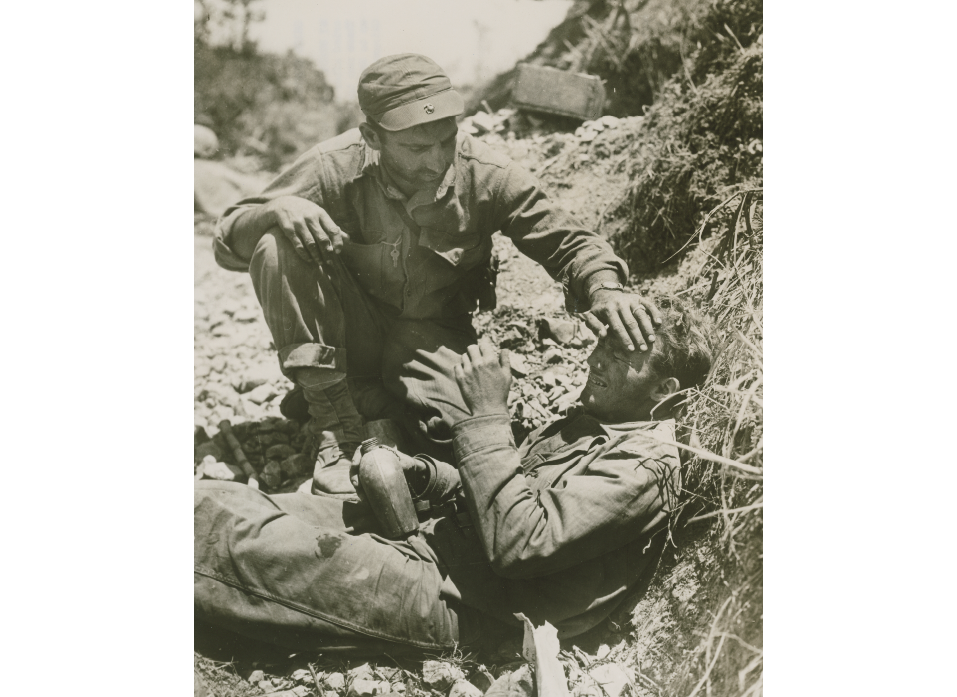 A 1st Division Marine comforts a fellow Marine who had just witnessed the death of his friend. US Navy official photograph. The National WWII Museum, Gift of Charles Ives, Accession #2011.102.602