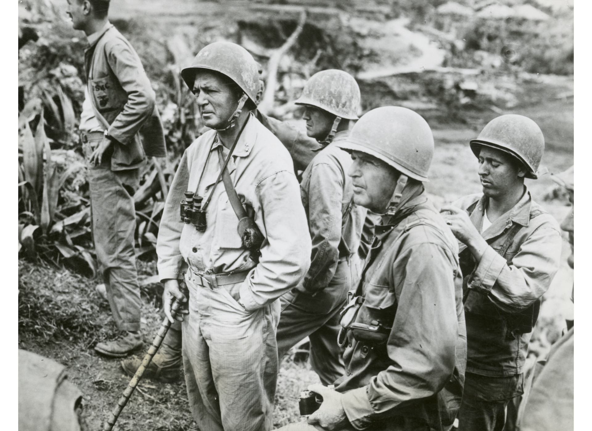 One of the last photographs taken of Lieutenant General Simon Bolivar Buckner (foreground, holding camera), he watches an assault from a ridge on Okinawa. US Marine Corps photograph. The National WWII Museum, Gift of Dylan Utley, Accession #2012.019.404