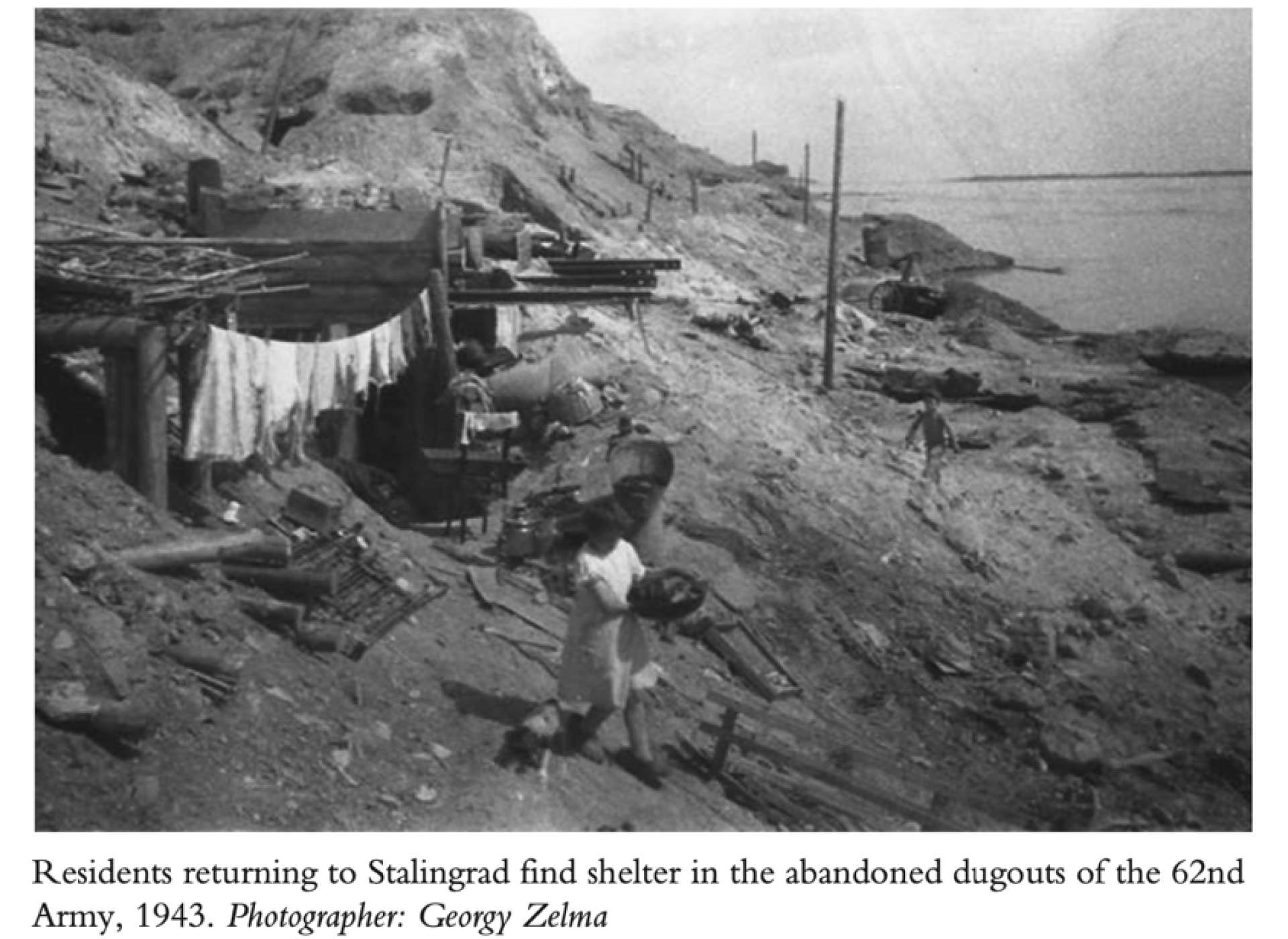 Residents returning to Stalingrad find shelter in the abandoned dugouts of the 62nd Army, 1943. Photographer: Georgy Zelma