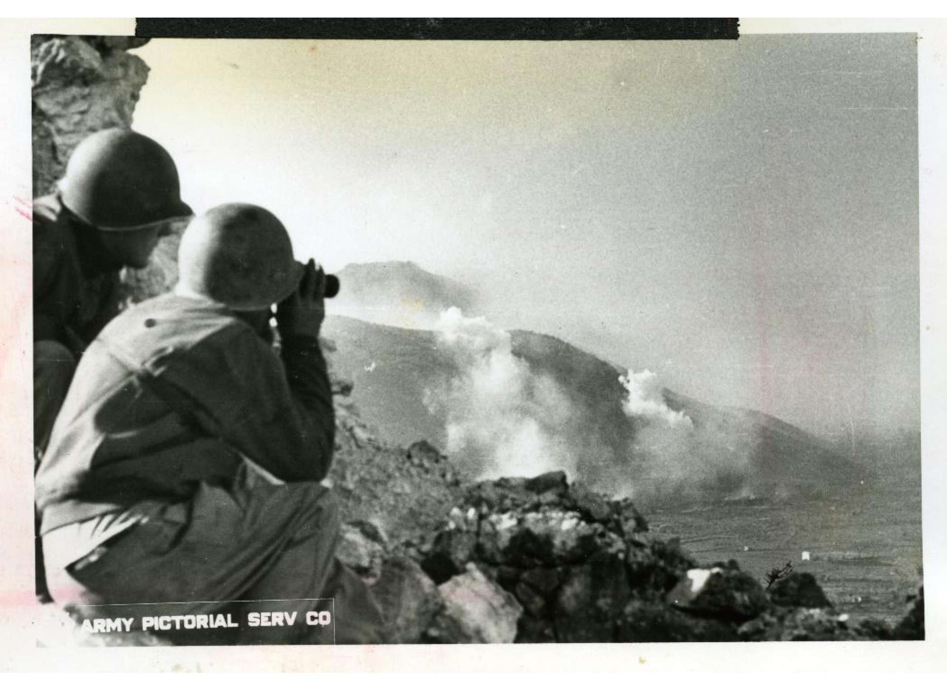 American artillery observers peer through their field glasses to watch enemy fortifications being shelled near San Pietro, Italy, 1943. Gift of Ms. Regan Forrester, 2002.337.414