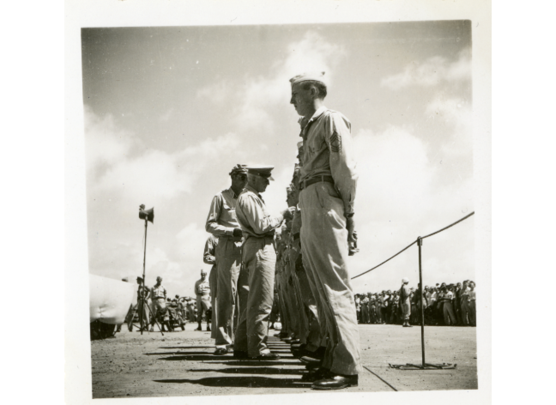 Members of the 20th Air Force line up to receive decorations. A large number of servicemen are gathered in the background to watch the ceremony. Gift of Donald Schlenger, 2014.153.031