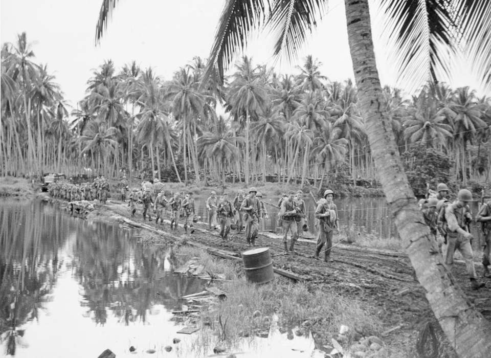 Soldiers walking by water at Guadalcanal during WWII