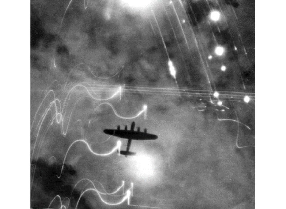 A Royal Air Force Lancaster bomber over Hamburg during Operation Gomorrah. Note the flares surrounding the bomber’s silhouette. 