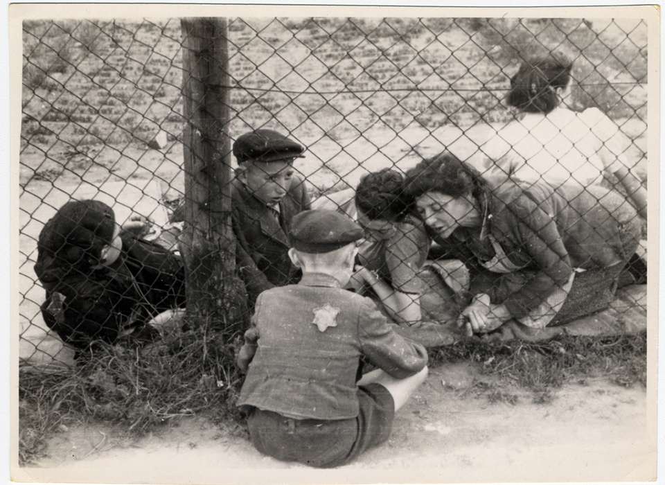 A child who has been selected for deportation, bids farewell to his family through the wire fence of the central prison, during the &quot;Gehsperre&quot; action in the Lodz ghetto
