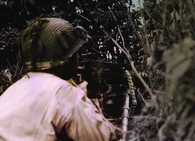 Soldier hides behind brush at The Battle for La Fière