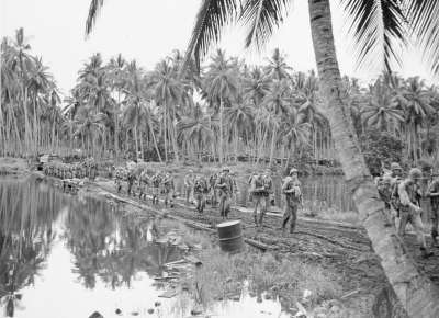 Soldiers walking by water at Guadalcanal during WWII