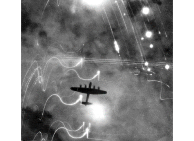 A Royal Air Force Lancaster bomber over Hamburg during Operation Gomorrah. Note the flares surrounding the bomber’s silhouette. 