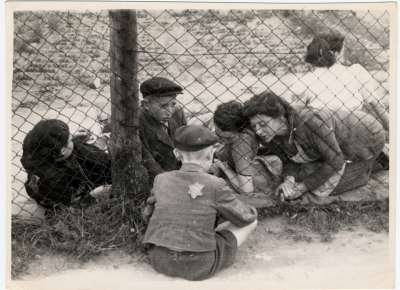 A child who has been selected for deportation, bids farewell to his family through the wire fence of the central prison, during the &quot;Gehsperre&quot; action in the Lodz ghetto